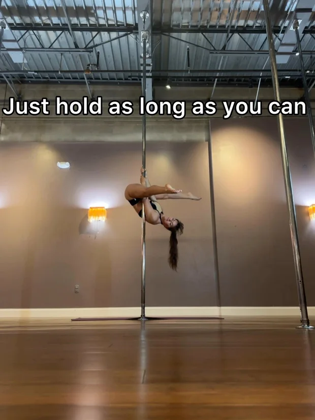 Polina Zueva inverted on the pole holding the shape, from the invert conditioning lesson.