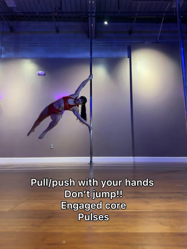 Polina Zueva horizontal on the pole in a red two-piece, from the twisted grip handspring lesson.