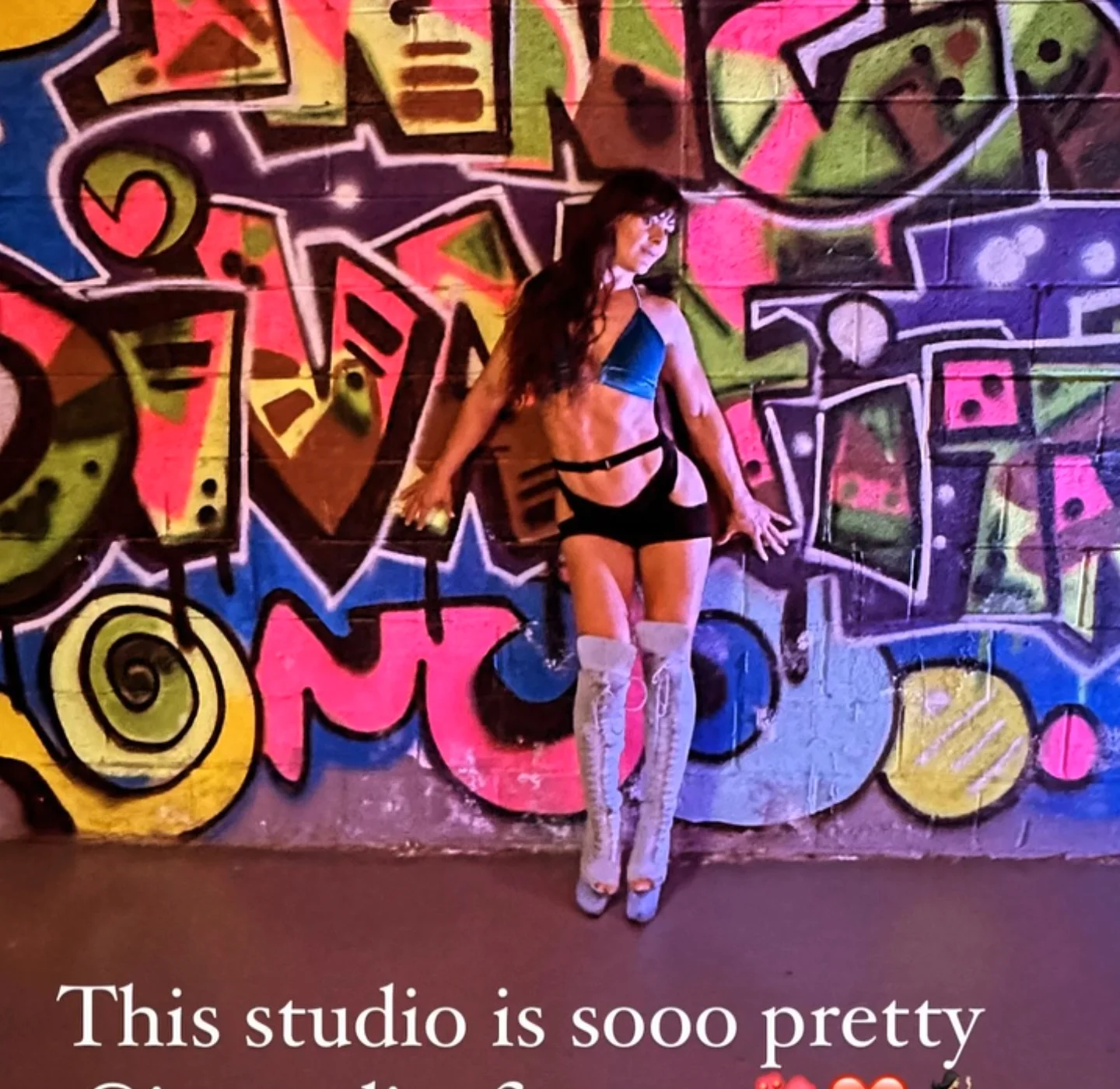 Polina Zueva against a graffiti wall at Inner Diva Fitness in Charlotte, in heels and a blue top.